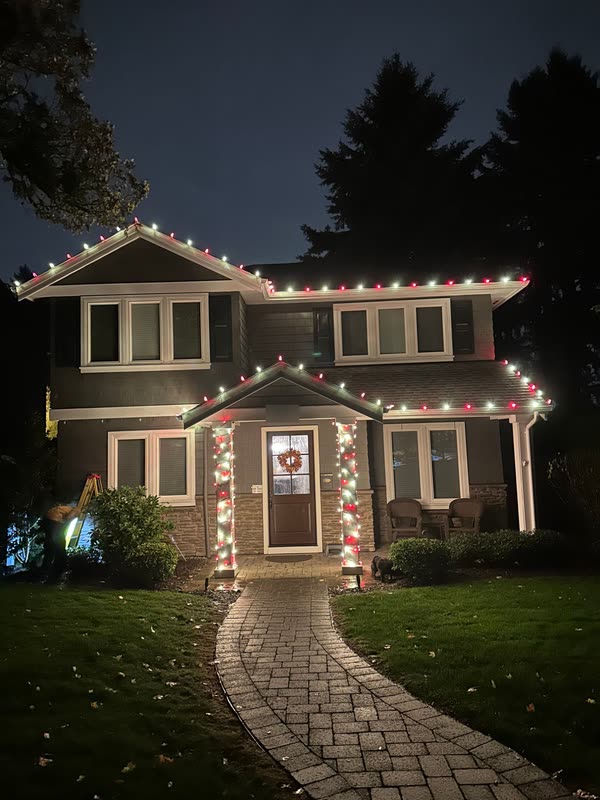 Craftsman-style home with alternating red and white C9 roofline lights and light-wrapped porch columns
